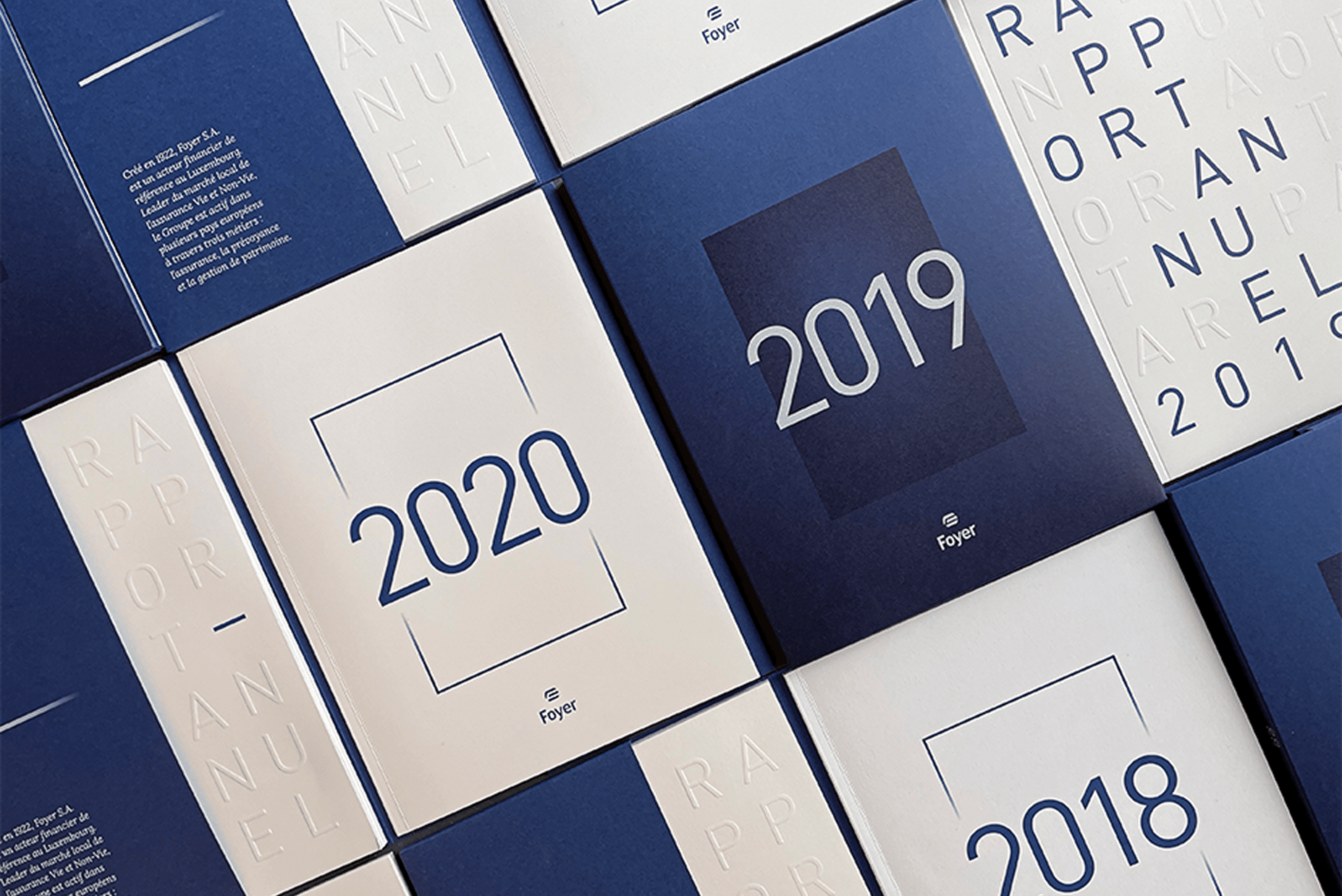Vue en gros plan de plusieurs rapports annuels empilés et arrangés en mosaïque, montrant des couvertures variées en bleu et blanc avec les années 2018, 2019 et 2020 clairement affichées en grand format.