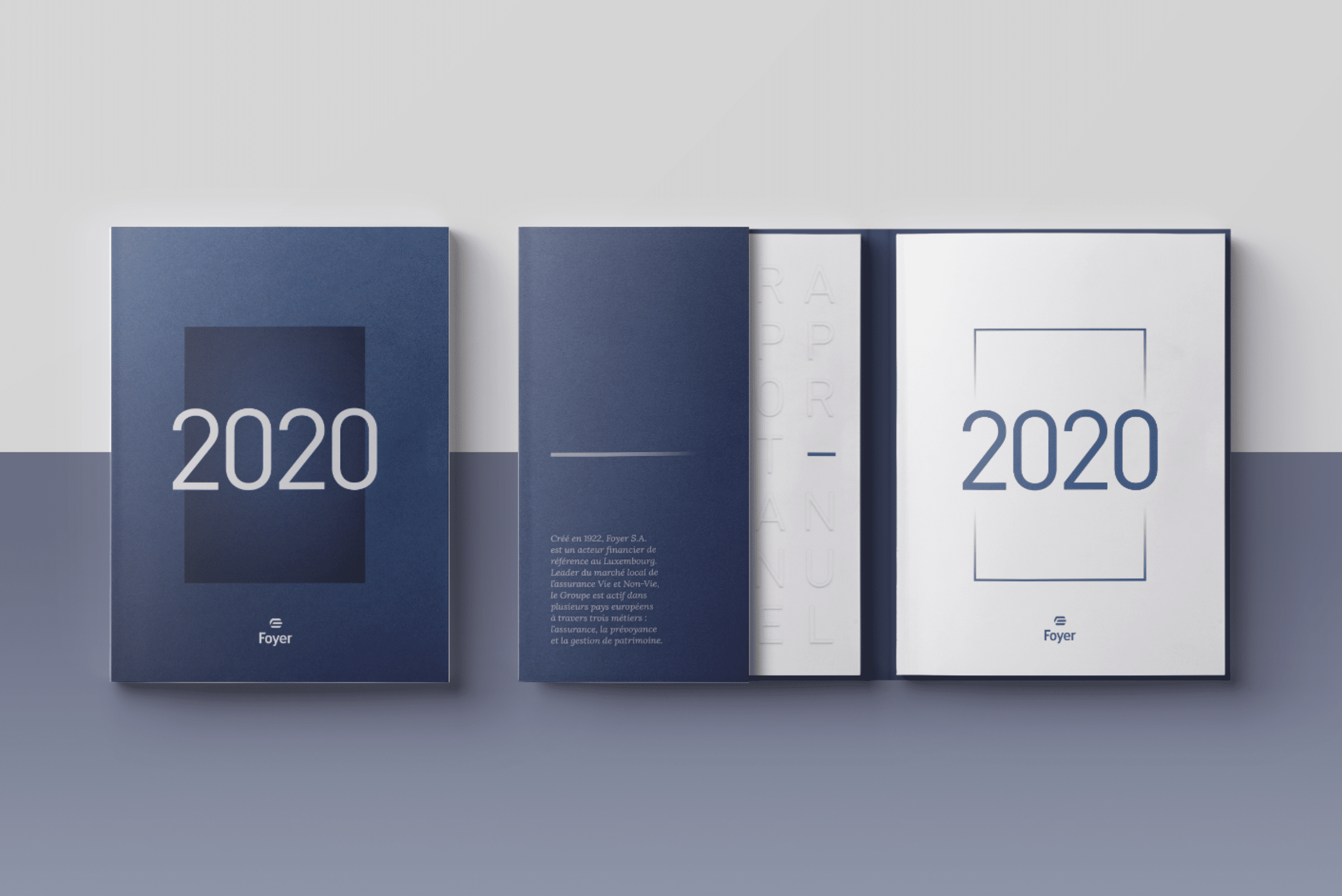 Trois rapports annuels de Foyer alignés, avec des couvertures en nuances de bleu, affichant le texte '2020' de manière proéminente; le rapport du milieu montre le texte 'RAPPORT ANNUEL' en relief sur la couverture.