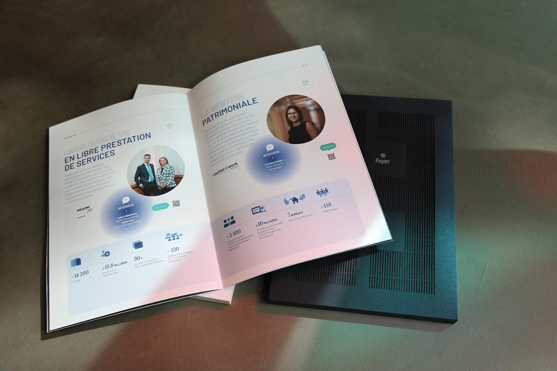 Deux brochures ouvertes sur une table, présentant des graphiques colorés et des photos de personnes avec des informations statistiques sur des services financiers, à côté du rapport annuel fermé avec une couverture texturée noire.